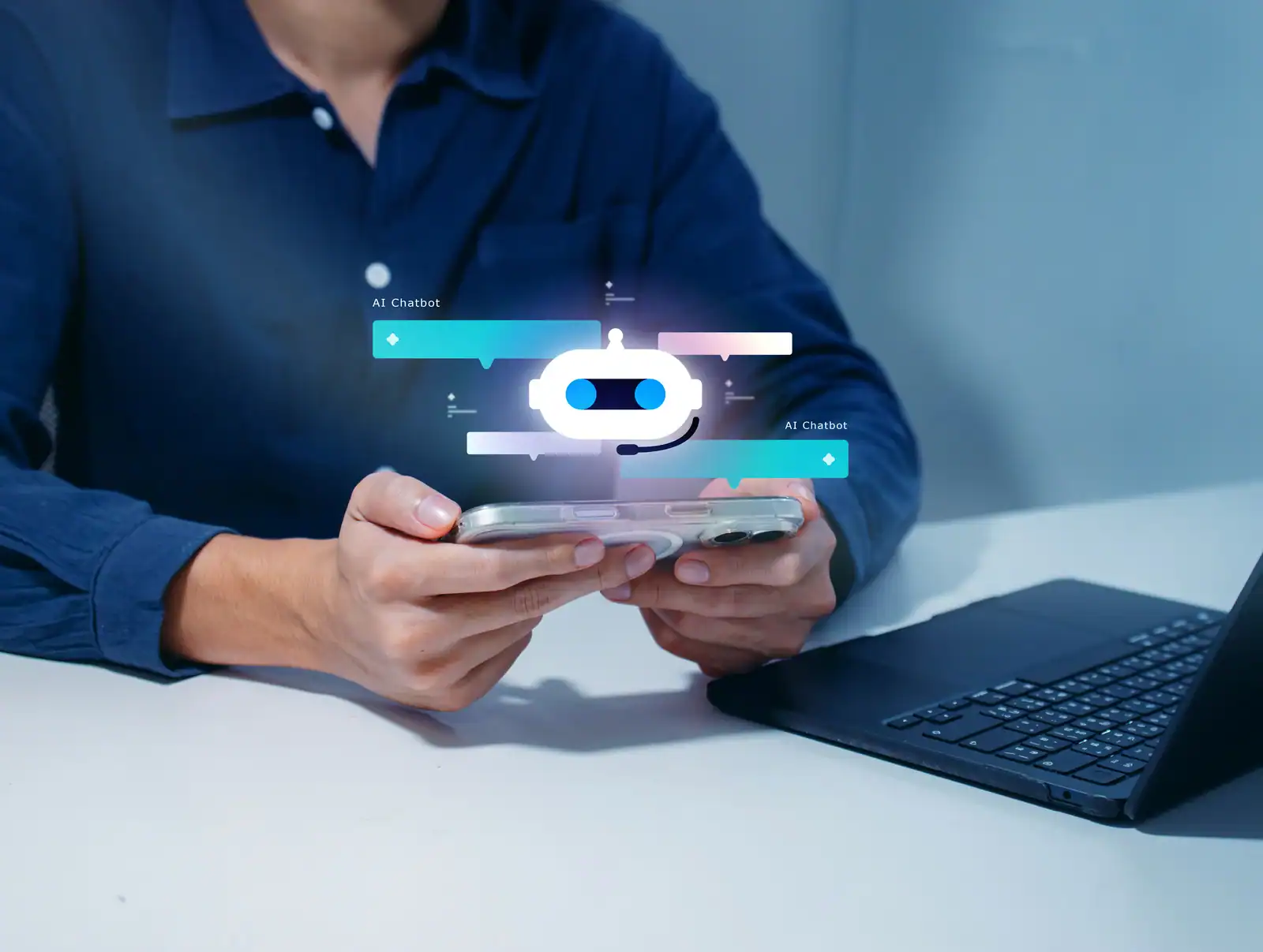 Person hält Smartphone mit KI-Chatbot-Icon über Laptop.
