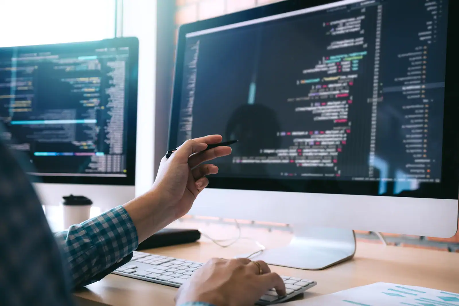 Programmierer arbeitet an Code auf einem großen Monitor.