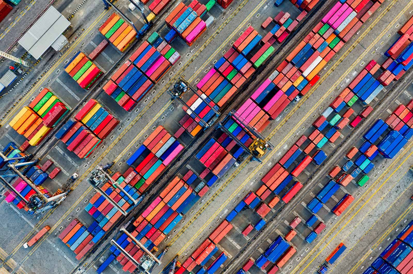 Containerlager mit bunten Containern und Zug auf Gleisen.
