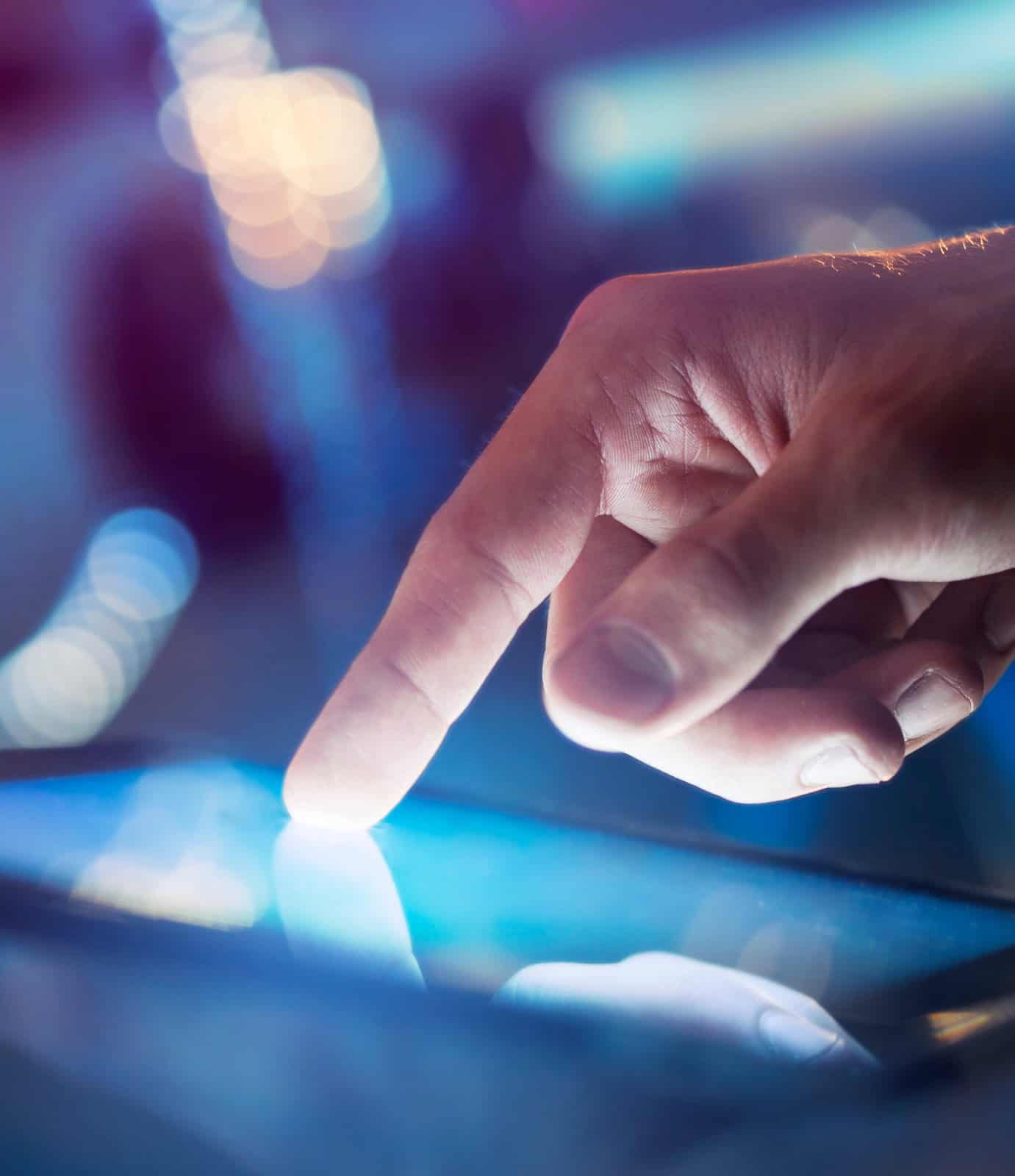 Finger tippt auf ein Smartphone-Display bei Nacht.