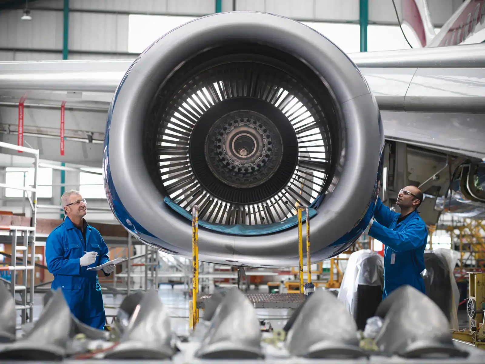 Zwei Techniker prüfen ein Flugzeugtriebwerk in der Fertigungshalle.