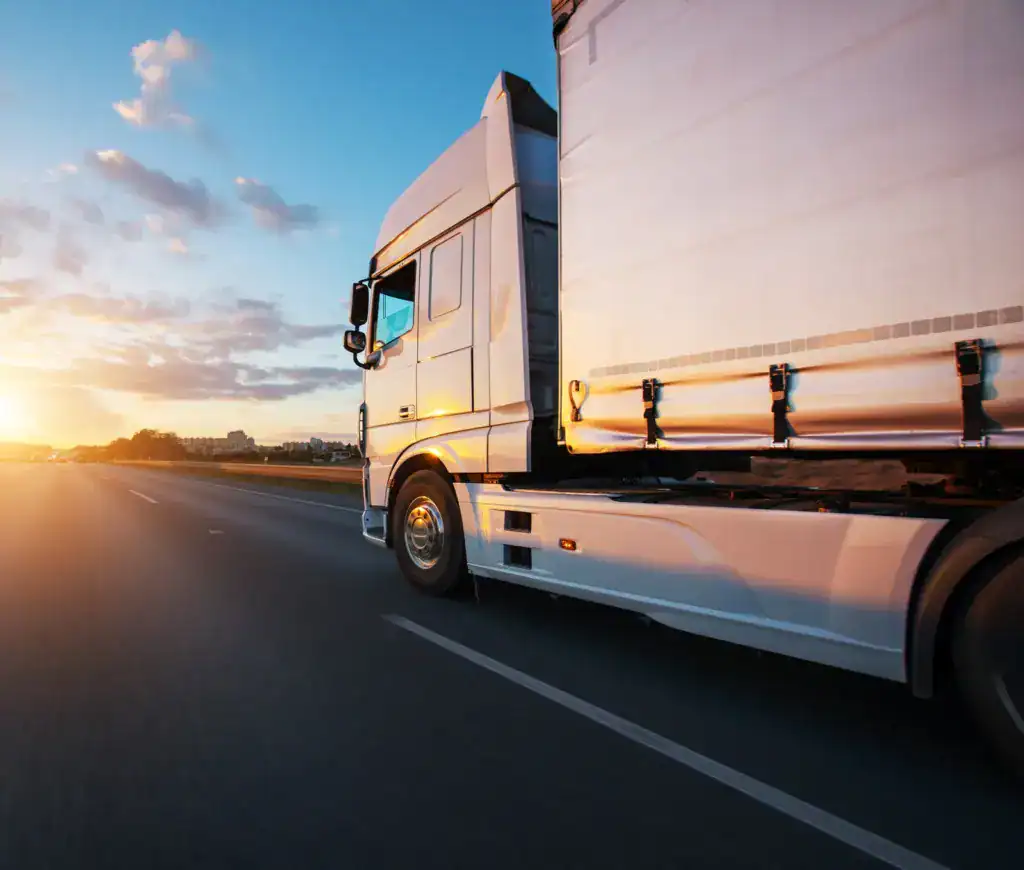 LKW fährt auf Autobahn bei Sonnenuntergang, Himmel mit Wolken und Sonnenstrahlen.